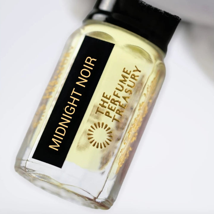 Close-up of Midnight Noir perfume oil by The Perfume Treasury showing the black and gold label and golden perfume oil.