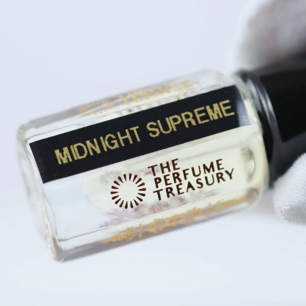 Close-up of Midnight Supreme attar perfume oil label by The Perfume Treasury, luxury fragrance oil bottle with gold text and clear glass detail.