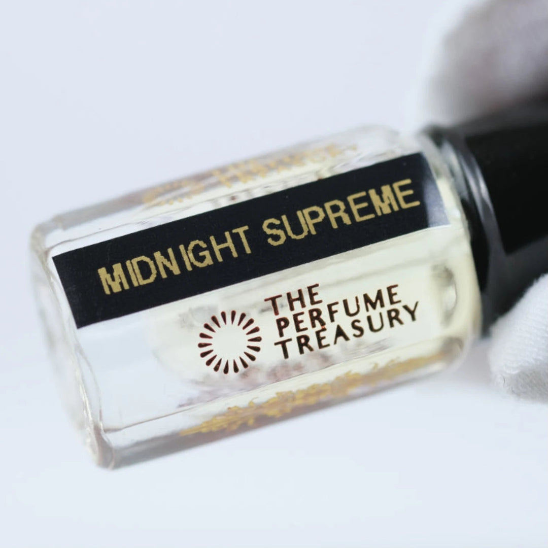 Close-up of Midnight Supreme attar perfume oil label by The Perfume Treasury, luxury fragrance oil bottle with gold text and clear glass detail.