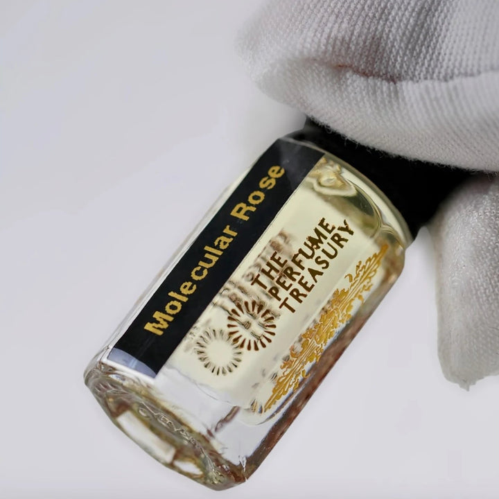 Close-up of Molecular Rose perfume oil by The Perfume Treasury showing the black and gold label and golden perfume oil.