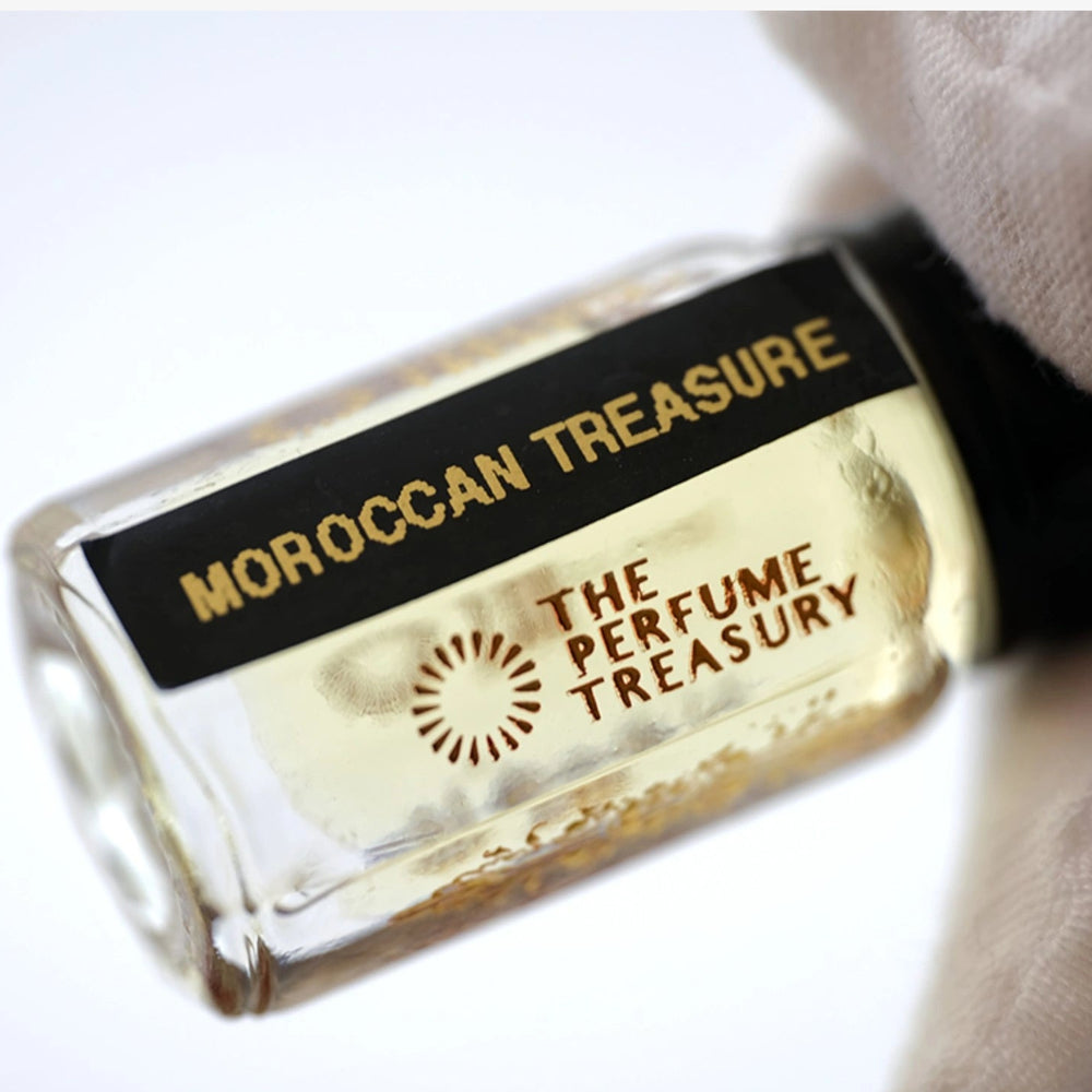 Close-up of Moroccan Treasure perfume oil showing warm amber liquid and intricate detailing.
