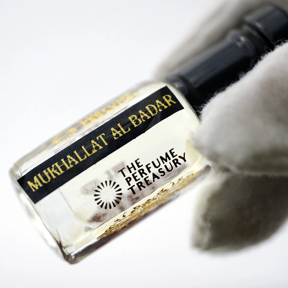 Close-up of Mukhallat Al Badar perfume oil by The Perfume Treasury showing the black and gold label and pale golden perfume oil.