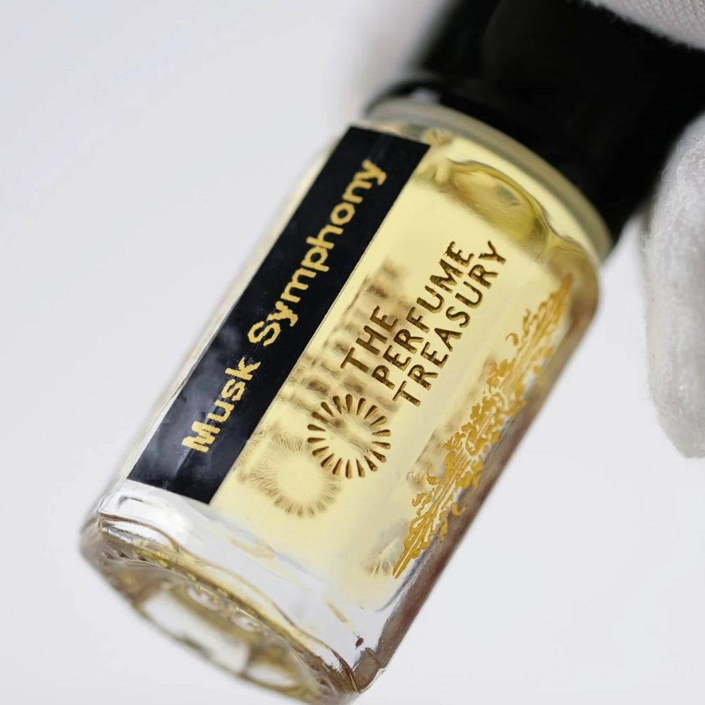 Close-up of Musk Symphony perfume oil by The Perfume Treasury showing the black and gold label and golden perfume oil.