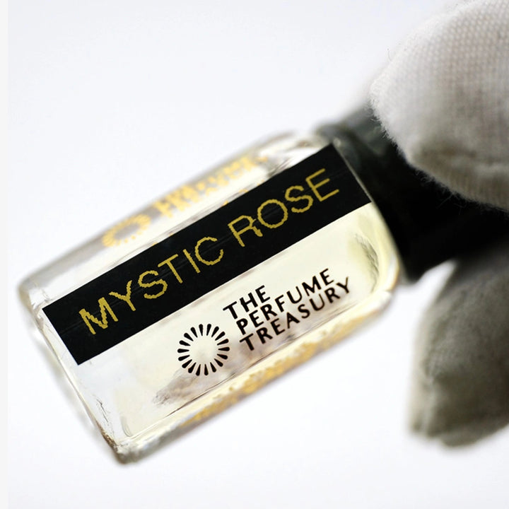 Close-up of Mystic Rose Musk Tahara perfume oil bottle held in white glove, showcasing delicate rose musk fragrance oil by The Perfume Treasury.