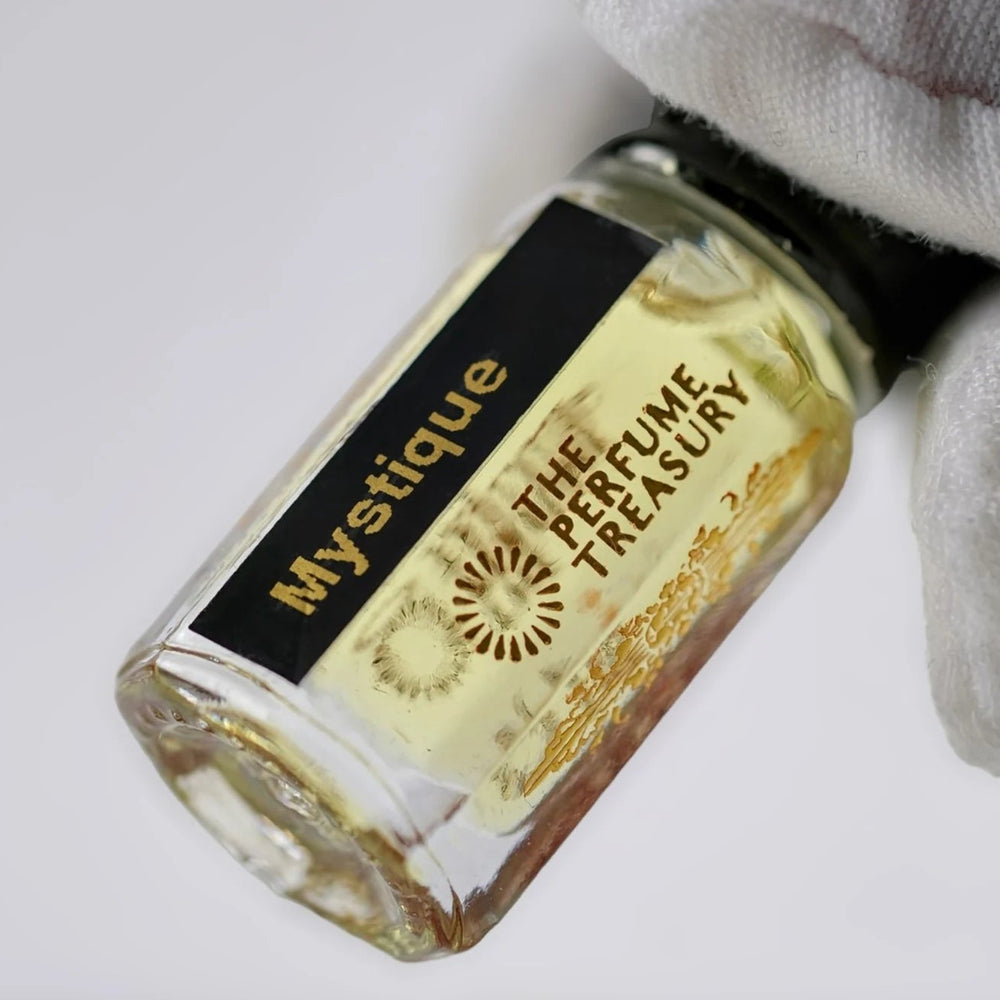 Close-up of Mystique perfume oil by The Perfume Treasury showing the black and gold label and golden perfume oil.