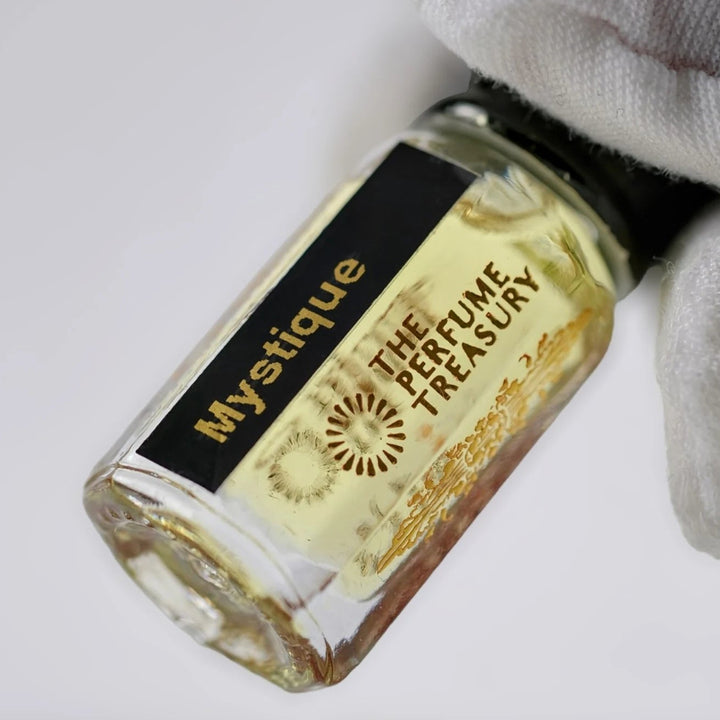 Close-up of Mystique perfume oil by The Perfume Treasury showing the black and gold label and golden perfume oil.