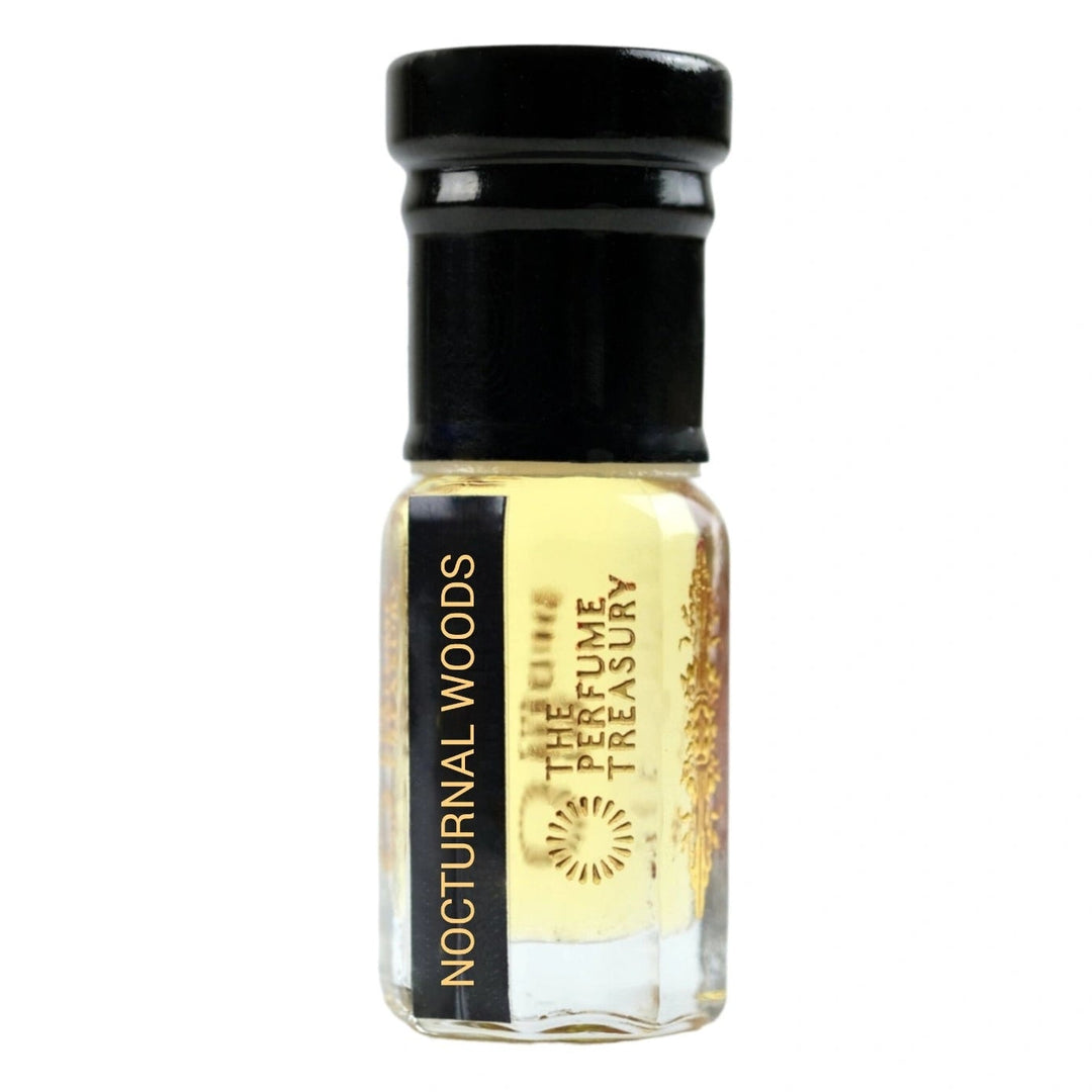 Small clear glass perfume oil bottle with black cap, Nocturnal Woods 3ml attar perfume oil by The Perfume Treasury, golden fragrance oil on white background.
