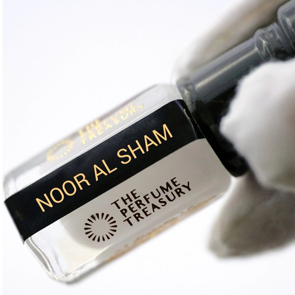 Close-up of Noor Al Sham Musk Tahara perfume oil bottle held in white glove, showcasing luxurious creamy musk fragrance oil by The Perfume Treasury.