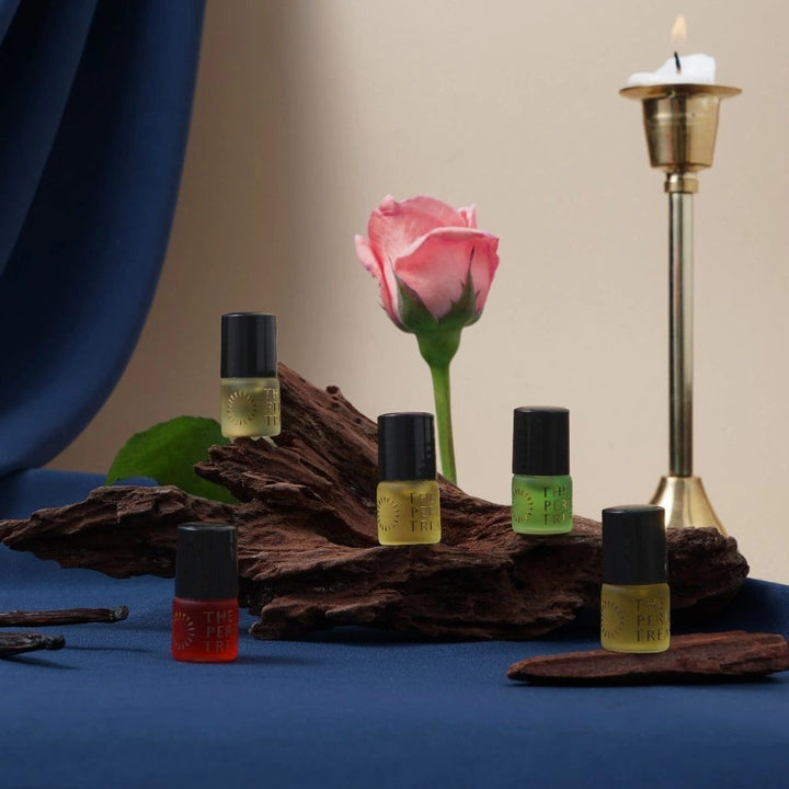 Oud inspired perfume oil collection displayed with wood, candle and rose, showcasing deep rich fragrance oils in a luxury setting