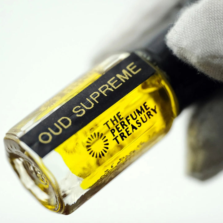 Oud Supreme perfume oil by The Perfume Treasury shown at an angle, highlighting the golden perfume oil and branded bottle.