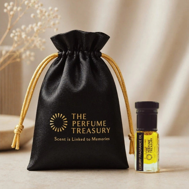 Black luxury gift pouch with gold logo and small clear glass perfume oil bottle, 3ml attar perfume oil by The Perfume Treasury, golden fragrance oil on neutral background.