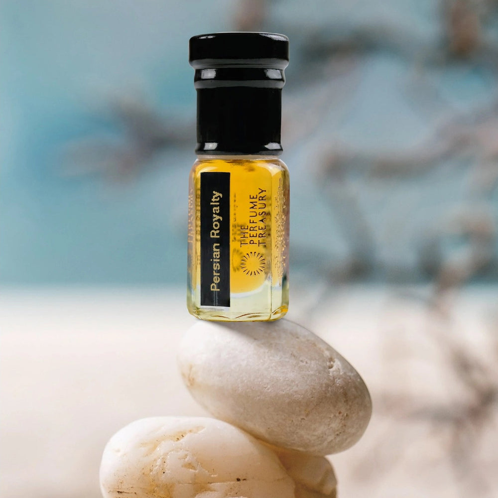 Persian Royalty 3ml attar perfume oil by The Perfume Treasury displayed on stacked stones, luxury golden fragrance oil in clear glass bottle with black cap.