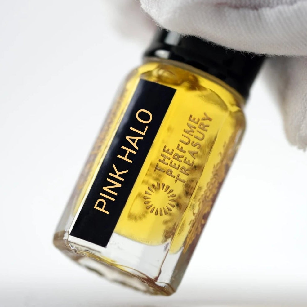 Pink Halo perfume oil by The Perfume Treasury held in a white-gloved hand, highlighting the golden perfume oil and branded bottle.