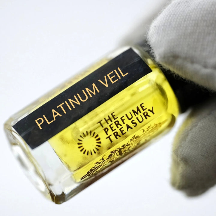 Platinum Veil perfume oil by The Perfume Treasury held in a white-gloved hand, highlighting the golden perfume oil and branded bottle.