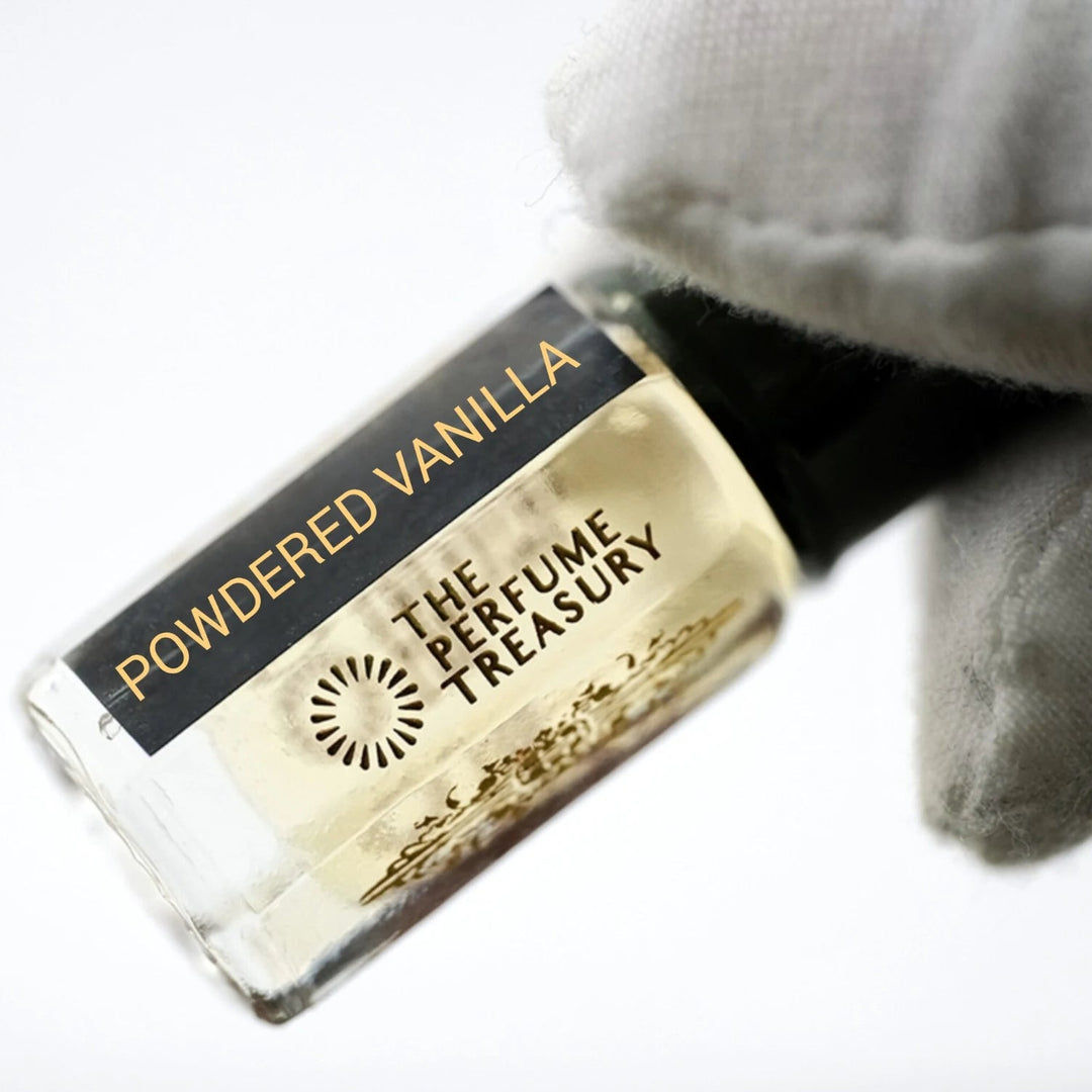 Powdered Vanilla perfume oil by The Perfume Treasury held in a white-gloved hand, showing the pale golden perfume oil and branded bottle.