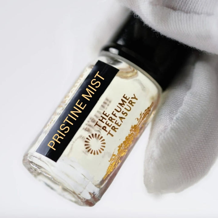 Pristine Mist perfume oil by The Perfume Treasury held in a white-gloved hand, highlighting the clear perfume oil and branded bottle.