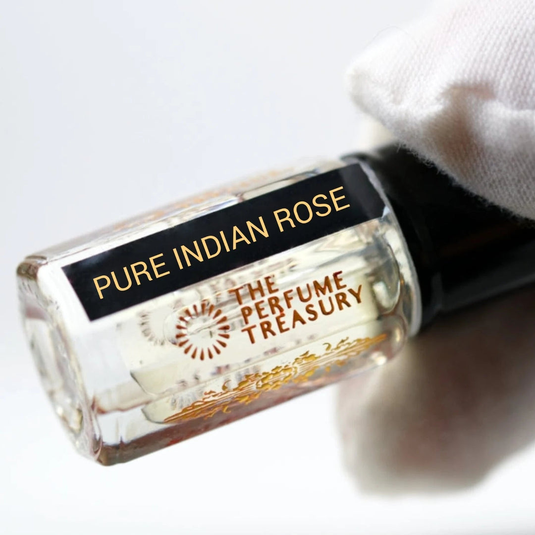 Pure Indian Rose perfume oil by The Perfume Treasury held in a white-gloved hand, showing the clear glass bottle and pale fragrance oil.