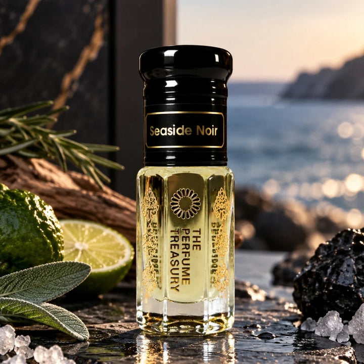 Seaside Noir perfume oil by The Perfume Treasury displayed by the coast with citrus, aromatic herbs, driftwood, sea salt crystals and dark volcanic rock.