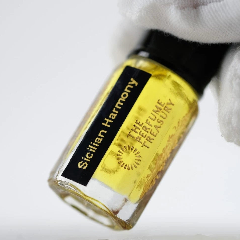 Sicilian Harmony perfume oil by The Perfume Treasury held in a white-gloved hand, highlighting the golden fragrance oil and elegant glass bottle.