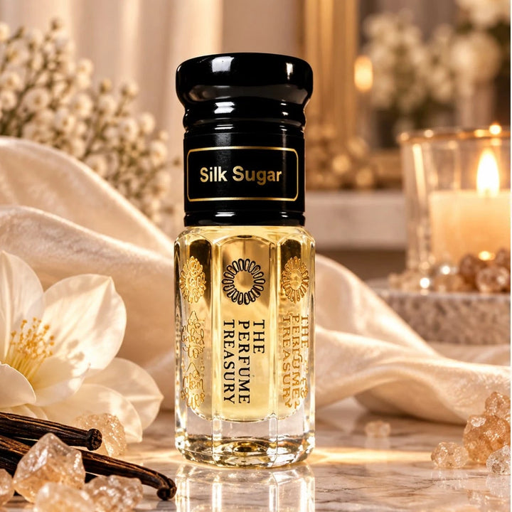 Silk Sugar luxury perfume oil bottle with black lid and golden fragrance oil displayed with white flowers, vanilla pods and sugar crystals in a warm elegant setting