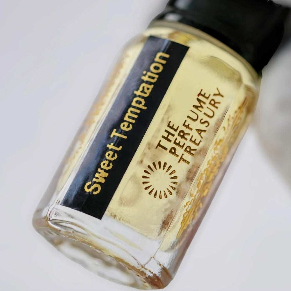 Sweet Temptation perfume oil by The Perfume Treasury shown close-up in a clear glass bottle with its signature black and gold label.