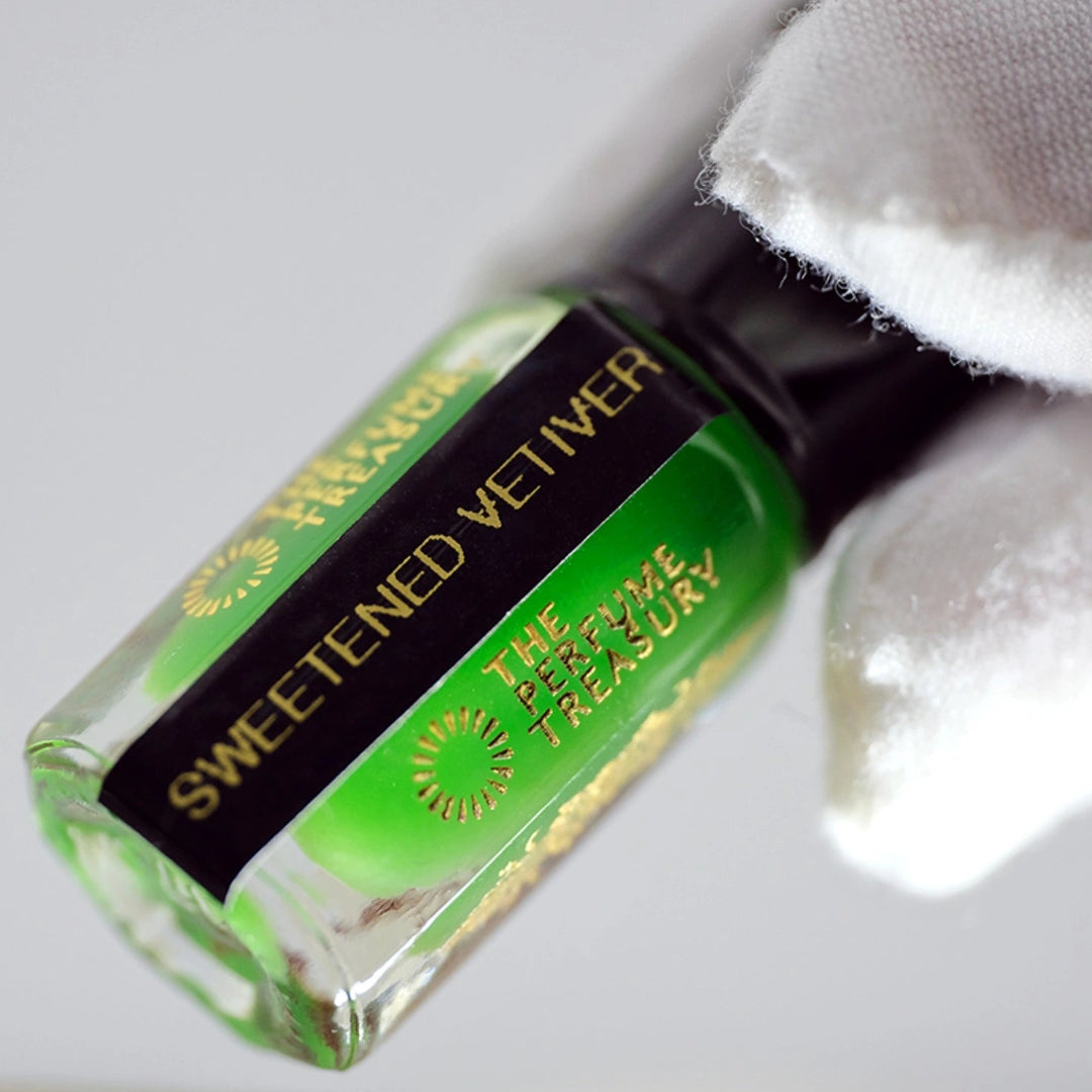 Close-up of Sweetened Vetiver Musk Tahara perfume oil bottle held in white glove, highlighting vibrant green vetiver musk fragrance oil by The Perfume Treasury.