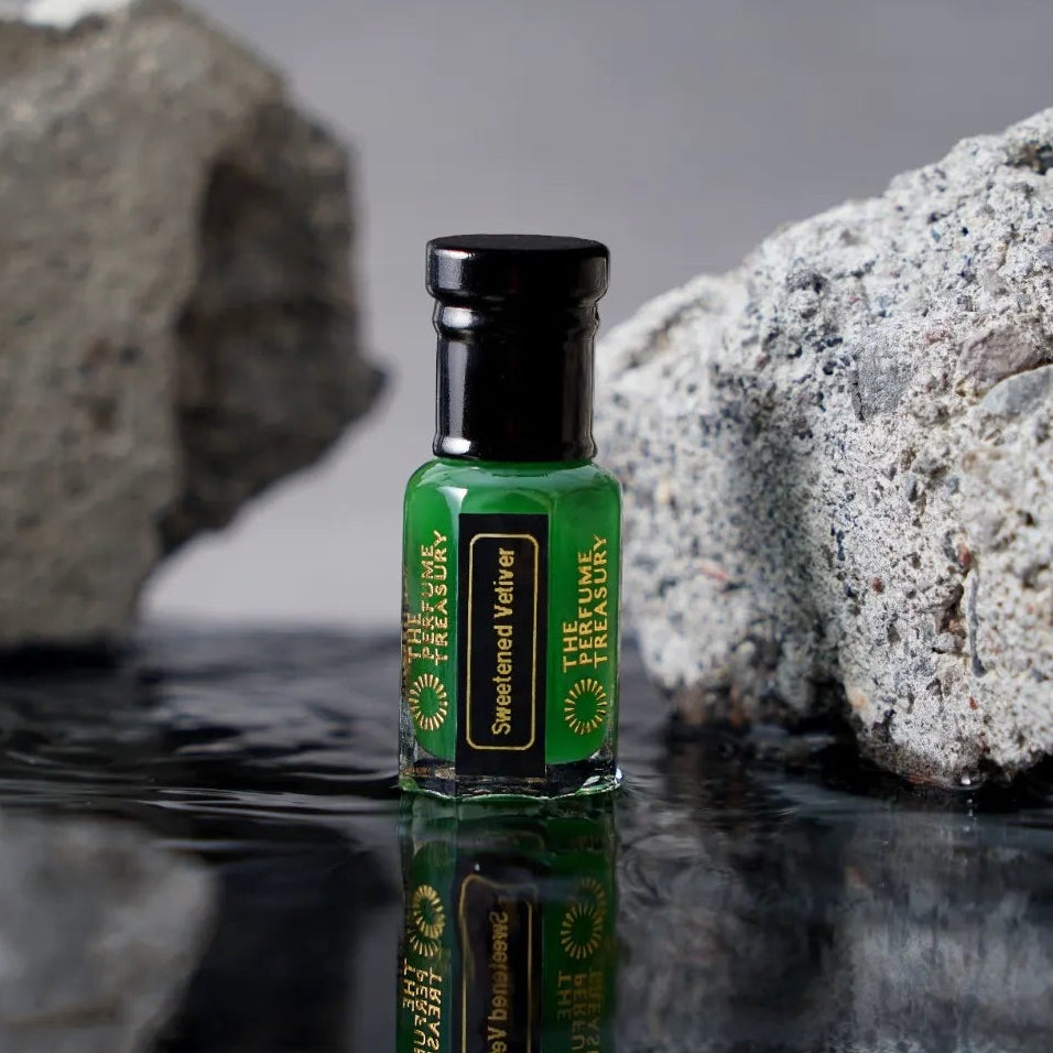 Sweetened Vetiver perfume oil bottle with reflective water surface and textured stone luxury fragrance backdrop.
