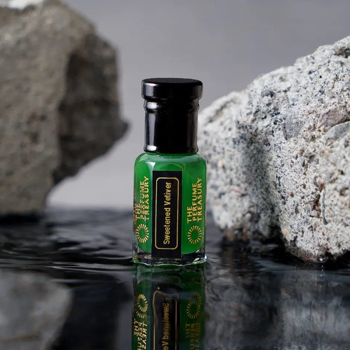 Sweetened Vetiver perfume oil bottle with reflective water surface and textured stone luxury fragrance backdrop.