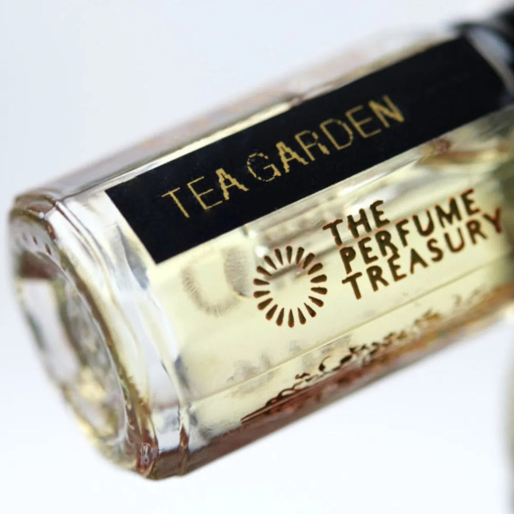 Close-up macro of Tea Garden 3ml attar perfume oil bottle by The Perfume Treasury, showing pale golden tea fragrance oil and glass detail, luxury perfume oil.