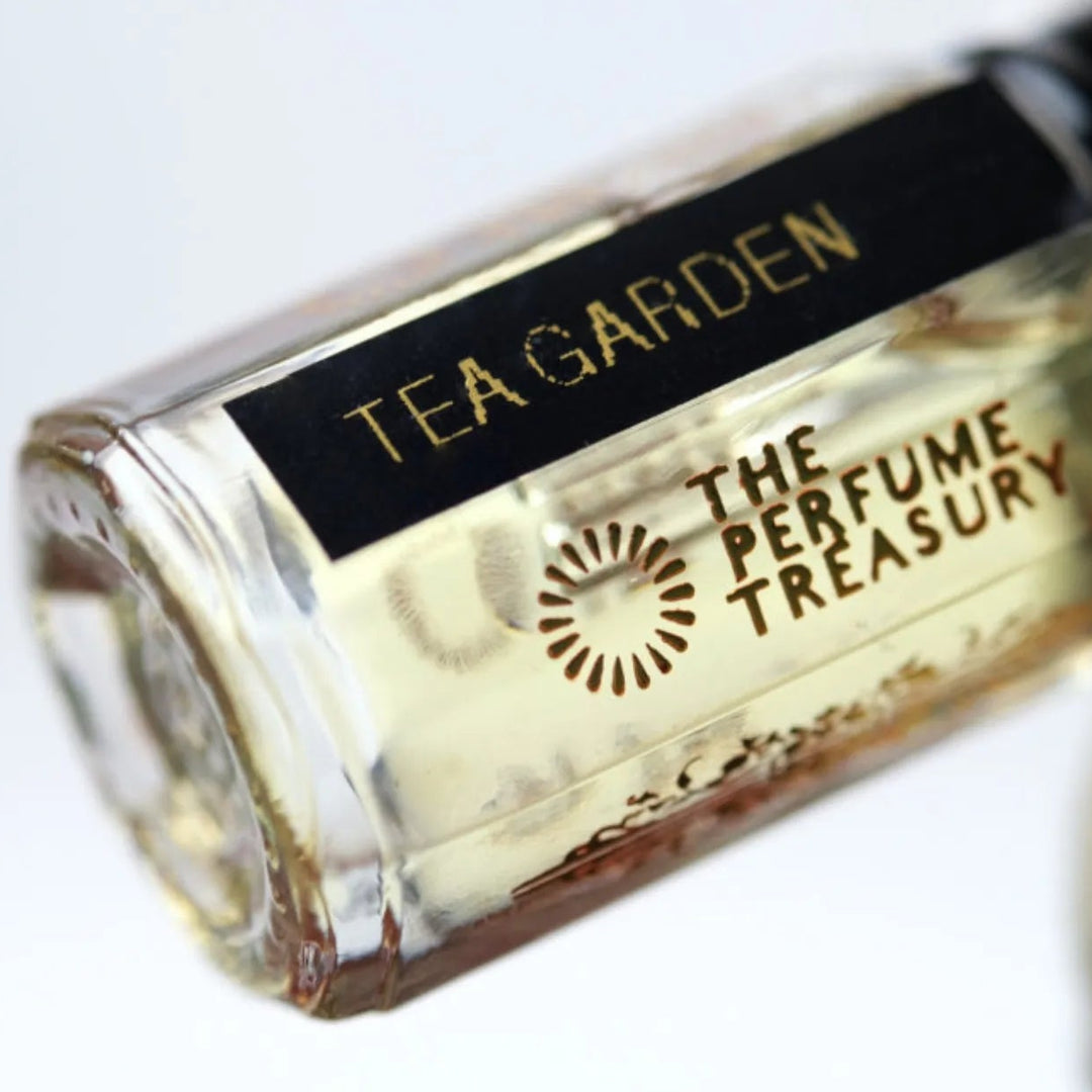 Close-up macro of Tea Garden 3ml attar perfume oil bottle by The Perfume Treasury, showing pale golden tea fragrance oil and glass detail, luxury perfume oil.