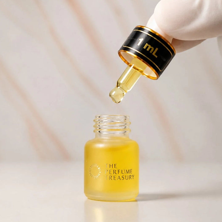 Close-up macro of The Perfume Treasury 1ml attar perfume oil bottle held with white glove, showing concentrated golden fragrance oil dropper and luxury finish, luxury Arabian fragrance oil in frosted glass bottle with black cap.