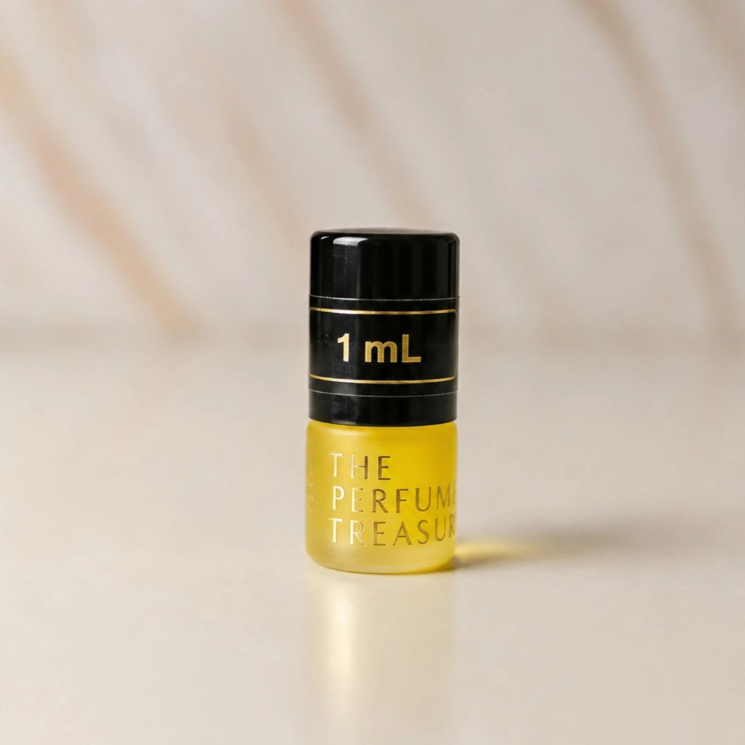Close-up macro of The Perfume Treasury 1ml attar perfume oil bottle, showing glossy yellow oil texture and minimalist luxury styling, concentrated perfume oil in frosted glass bottle with black cap.