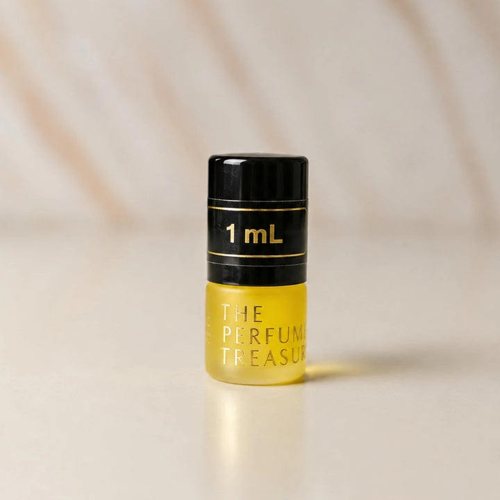 Close-up macro of The Perfume Treasury 1ml attar perfume oil bottle, showing glossy yellow oil texture and minimalist luxury styling, concentrated perfume oil in frosted glass bottle with black cap.