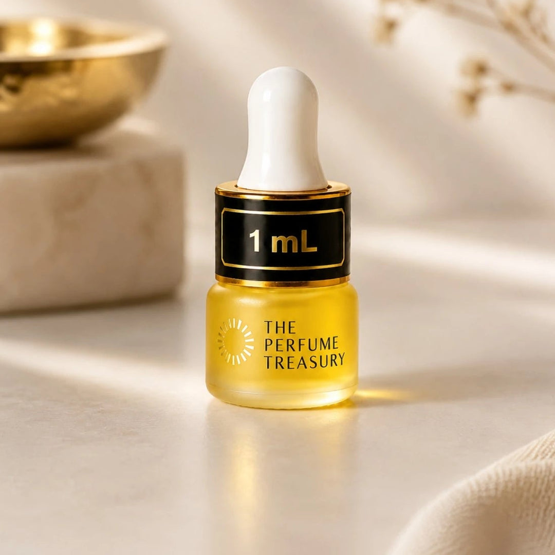Close-up macro of The Perfume Treasury 1ml attar perfume oil bottle, showing warm golden oil texture and elegant dropper applicator, luxury Arabian fragrance oil in frosted glass bottle with black cap.