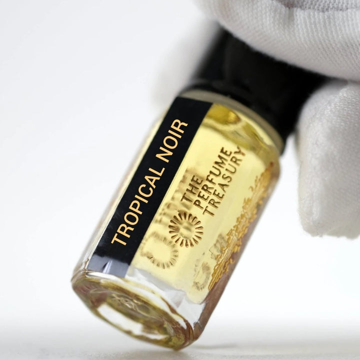Close-up of Tropical Noir perfume oil by The Perfume Treasury in a clear glass bottle with black and gold label