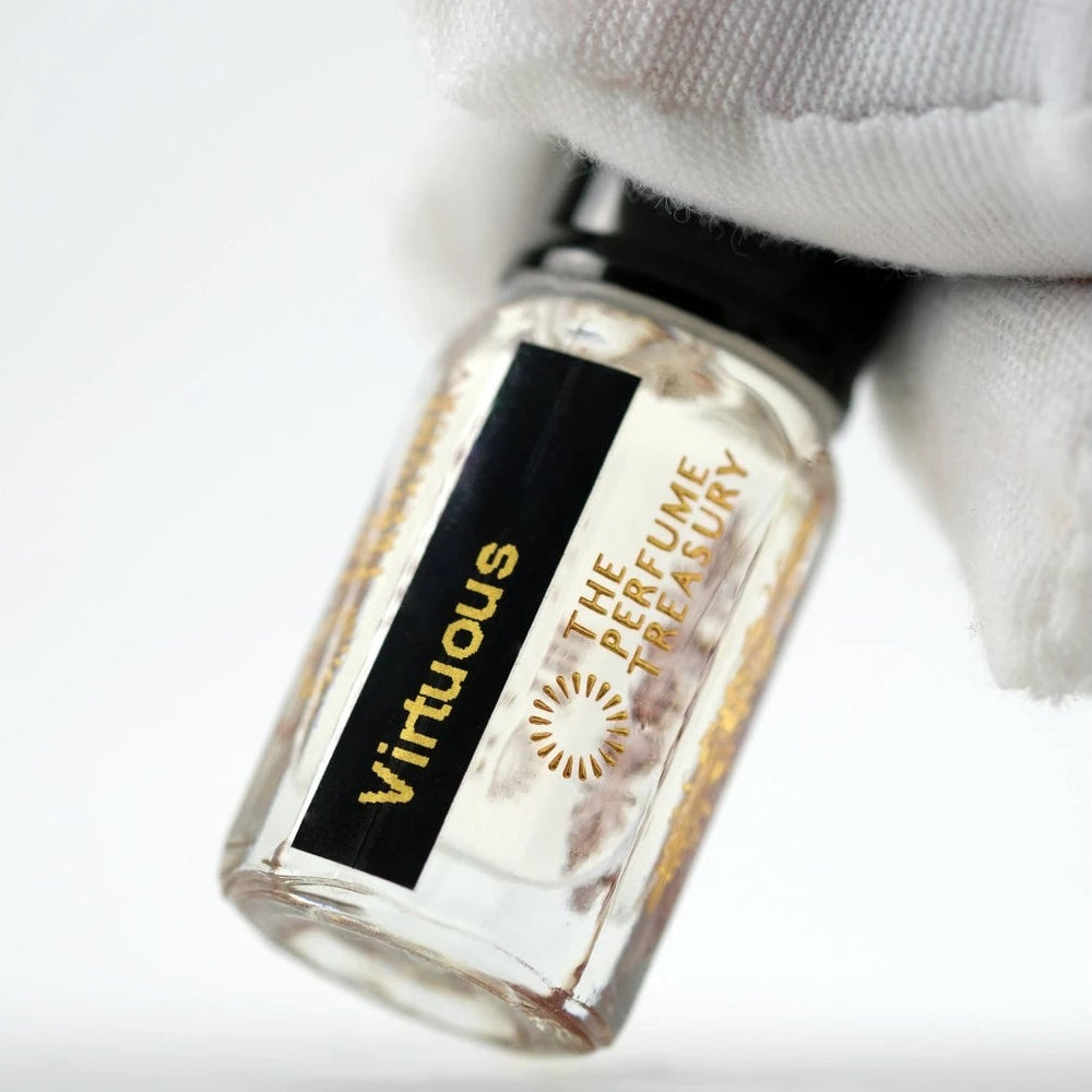 Close-up of Virtuous attar perfume oil bottle held with white glove, premium fragrance oil by The Perfume Treasury with clear glass and gold detailing.