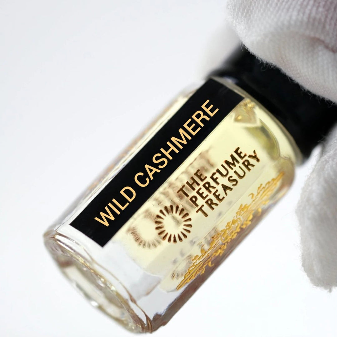 Close-up of Wild Cashmere perfume oil by The Perfume Treasury showing the pale golden oil and branded bottle label