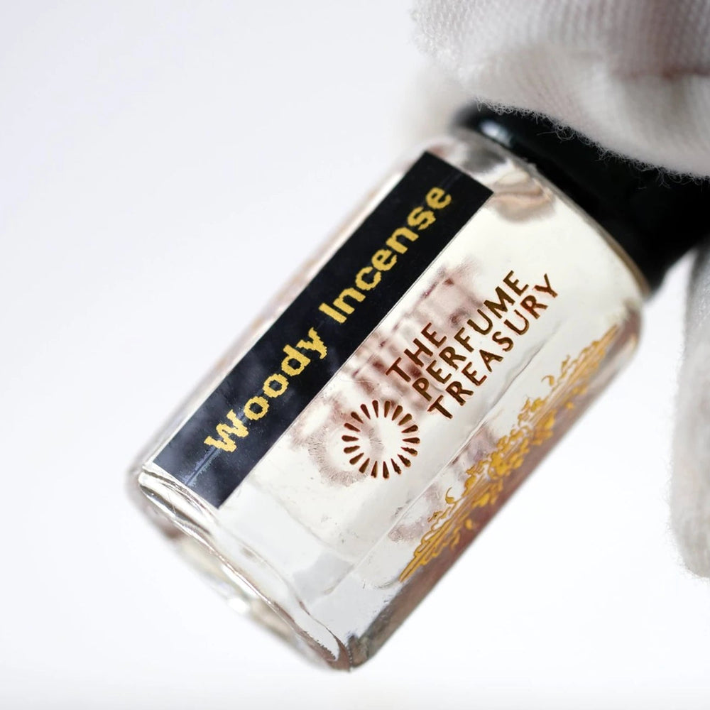 Close-up of Woody Incense perfume oil by The Perfume Treasury showing the branded glass bottle and clear perfume oil
