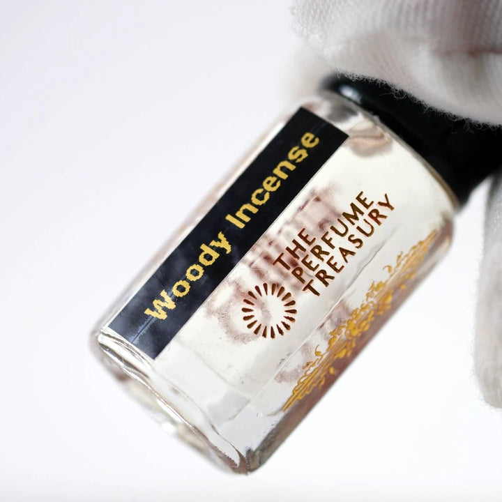 Close-up of Woody Incense perfume oil by The Perfume Treasury showing the branded glass bottle and clear perfume oil